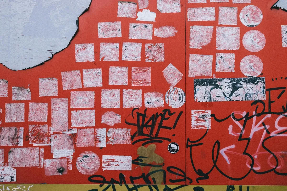 Mur rouge couvert de traces d'affiches et de flyers arrachés