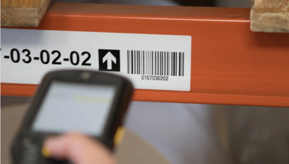 Étiquette TroLase code-barres sur rayonnage d'entrepôt, scanner portable en action