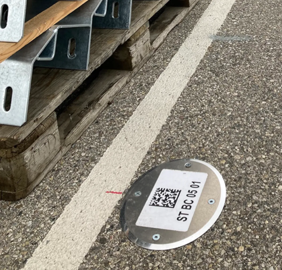 Étiquette TroLase avec QR code collée sur sol béton pour traçabilité terrain en entrepôt